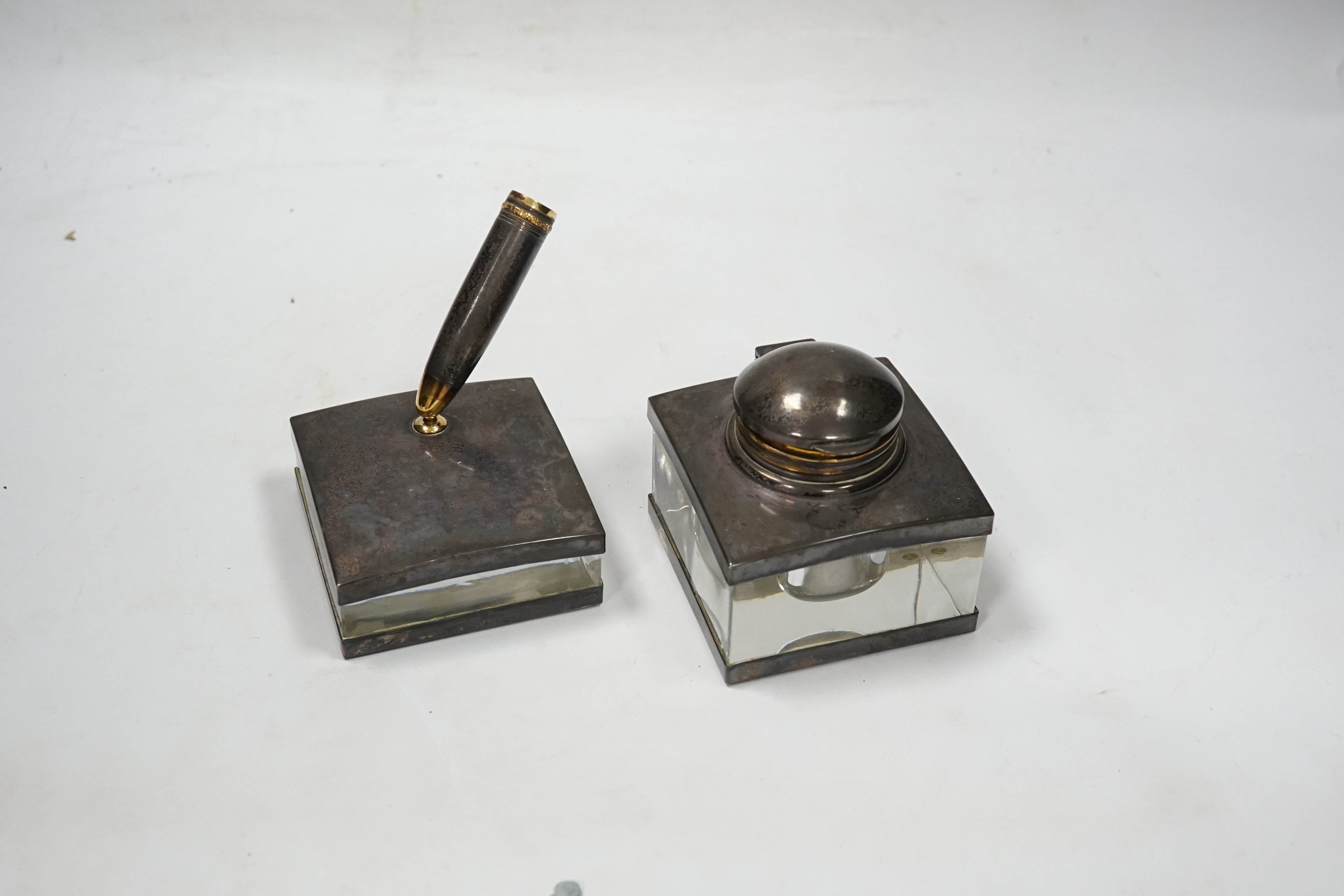 A Montblanc three piece German silver and glass desk set comprising pen stand, inkwell and blotter, each glass mounted, silver engraved with the Montblanc logo